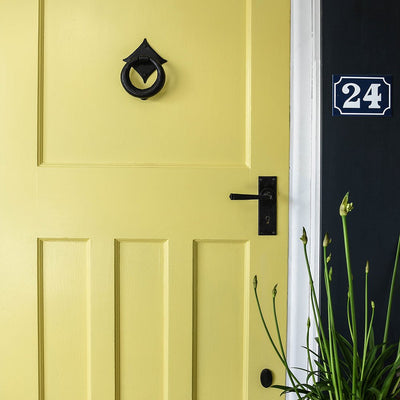 A yellow door with the Berkeley escutcheon fitted with a lever handle and a Ring door knocker