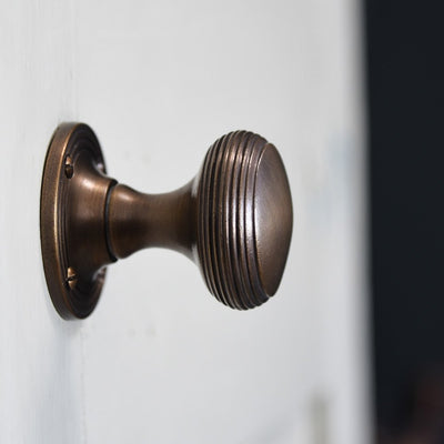 Close view of solid brass Reeded Cushion Door Knobs in Distressed Antique finish.