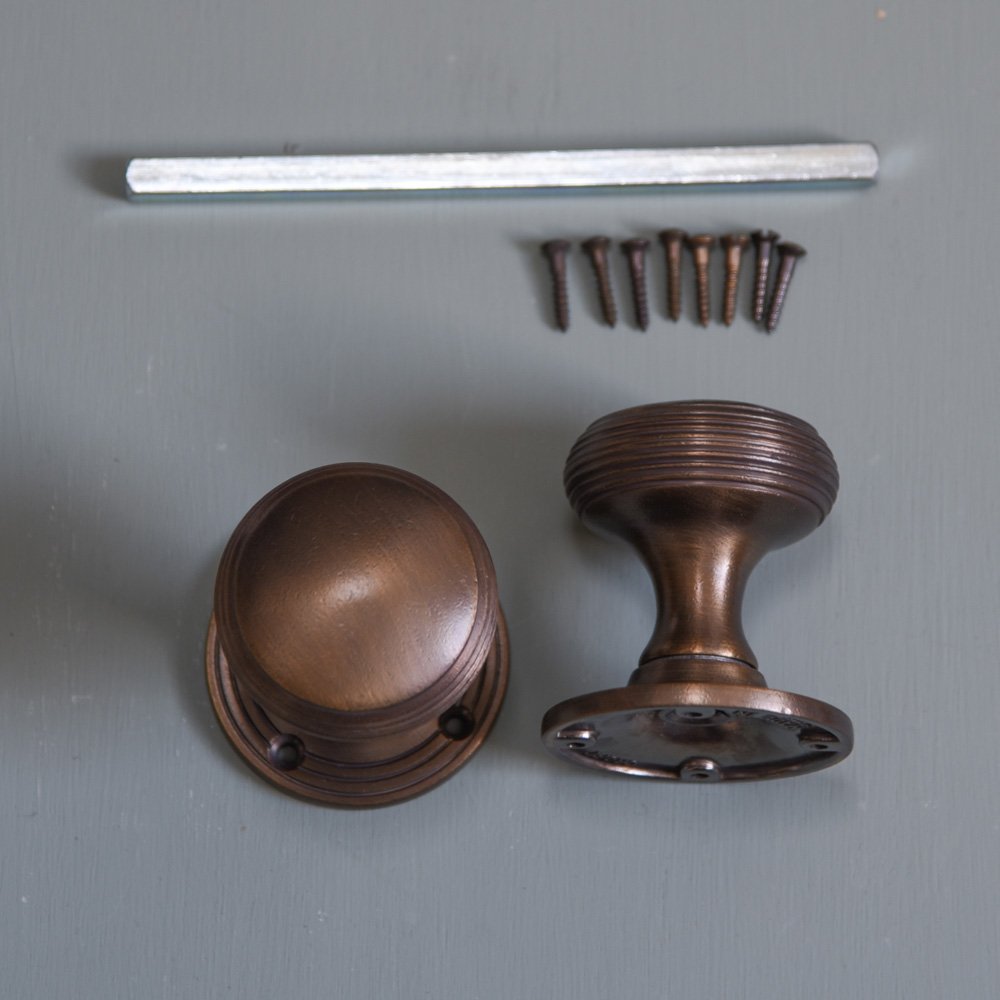 Components of Reeded Cushion Door Knobs in Distressed Antique finish including 2x door knobs, screws and spindle.