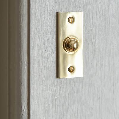 Alternate angle of Rectangular Brass Bell Push on white door