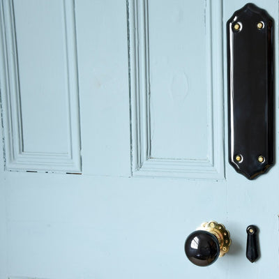 Black Ceramic Door Knobs with Brass Petal Backplates on Door With Matching Black Ceramic Escutcheon and Fingerplate