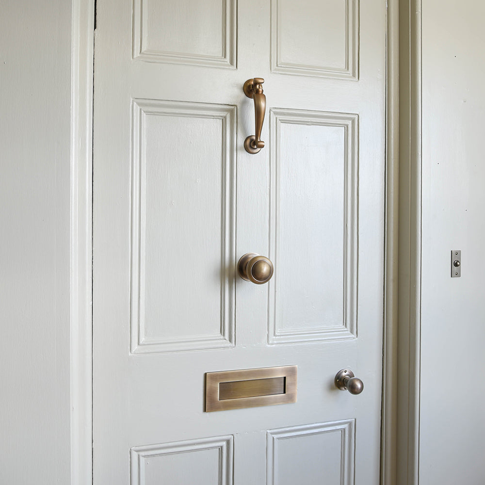 Light Antique Brass door furniture on off-white door.