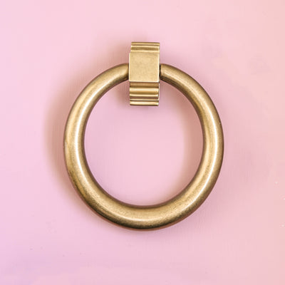 Solid brass Large Hoop Door Knocker with aged finish on pink painted wood.
