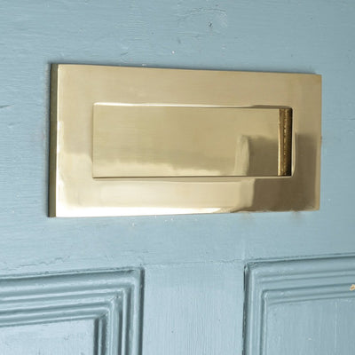 Close up of Plain Polished Brass Letterplate on blue door.