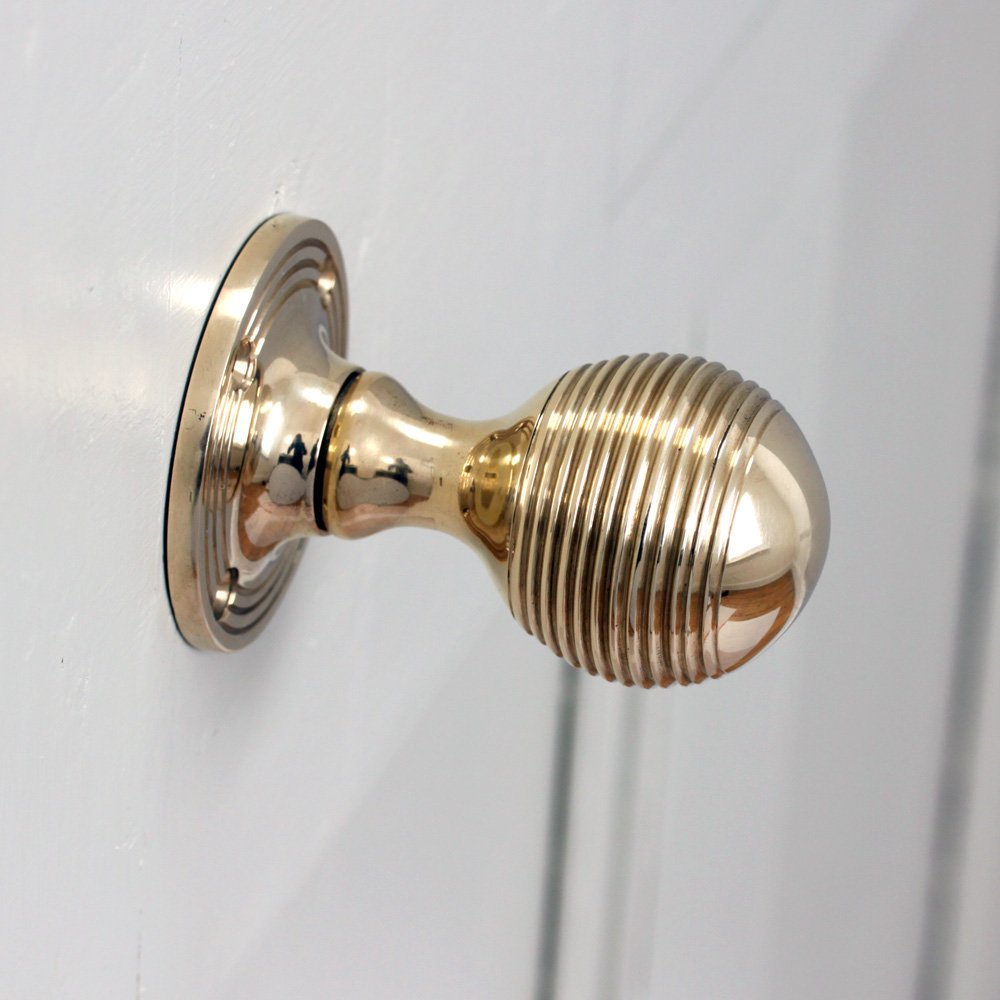 A Reeded Beehive Door Knob in Polished Brass Finish to a Light Grey Door