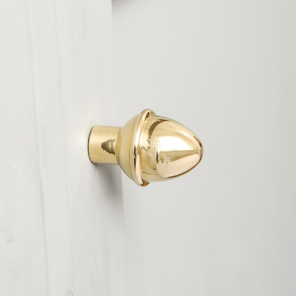 Acorn Shaped Cabinet Knob in a Polished Brass finish fitted to a white cabinet door