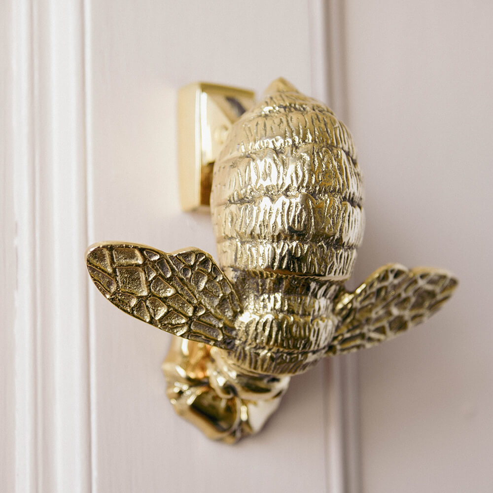 Brass bumble bee door knocker with flower strike plate on pale pink door