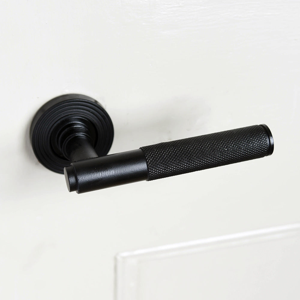 A Brompton lever handle in a matte black finish fitted to a door