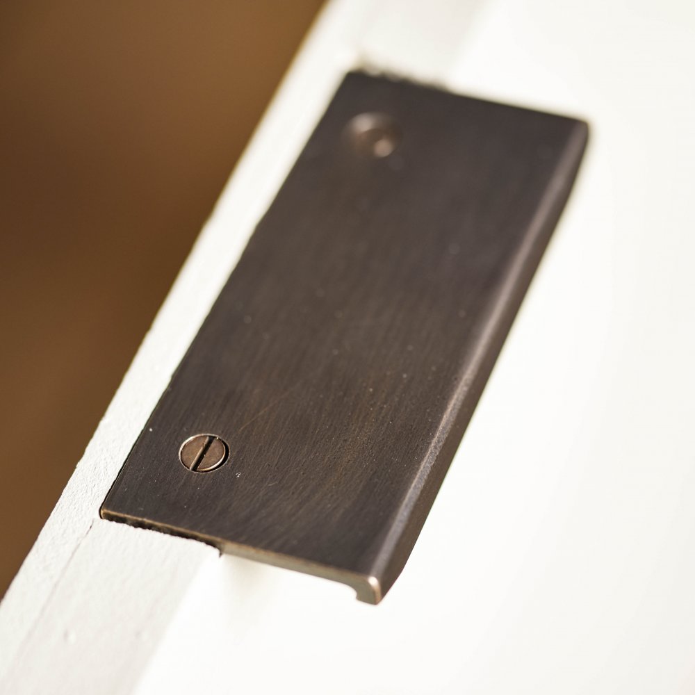 Finish detail of solid brass Tapered Cabinet Edge Pull in Distressed Antique.