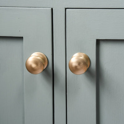 Green cupboard doors with Satin Brass Cabinet Knobs.