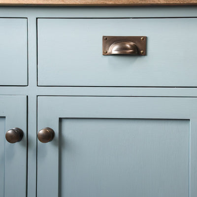 Distressed Antique Brass Cabinet Knobs and Hooded Pull on Blue Cabinet