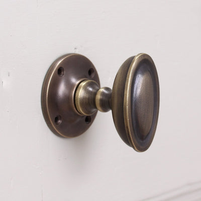 Antique brass oval door knob with ridged detail
