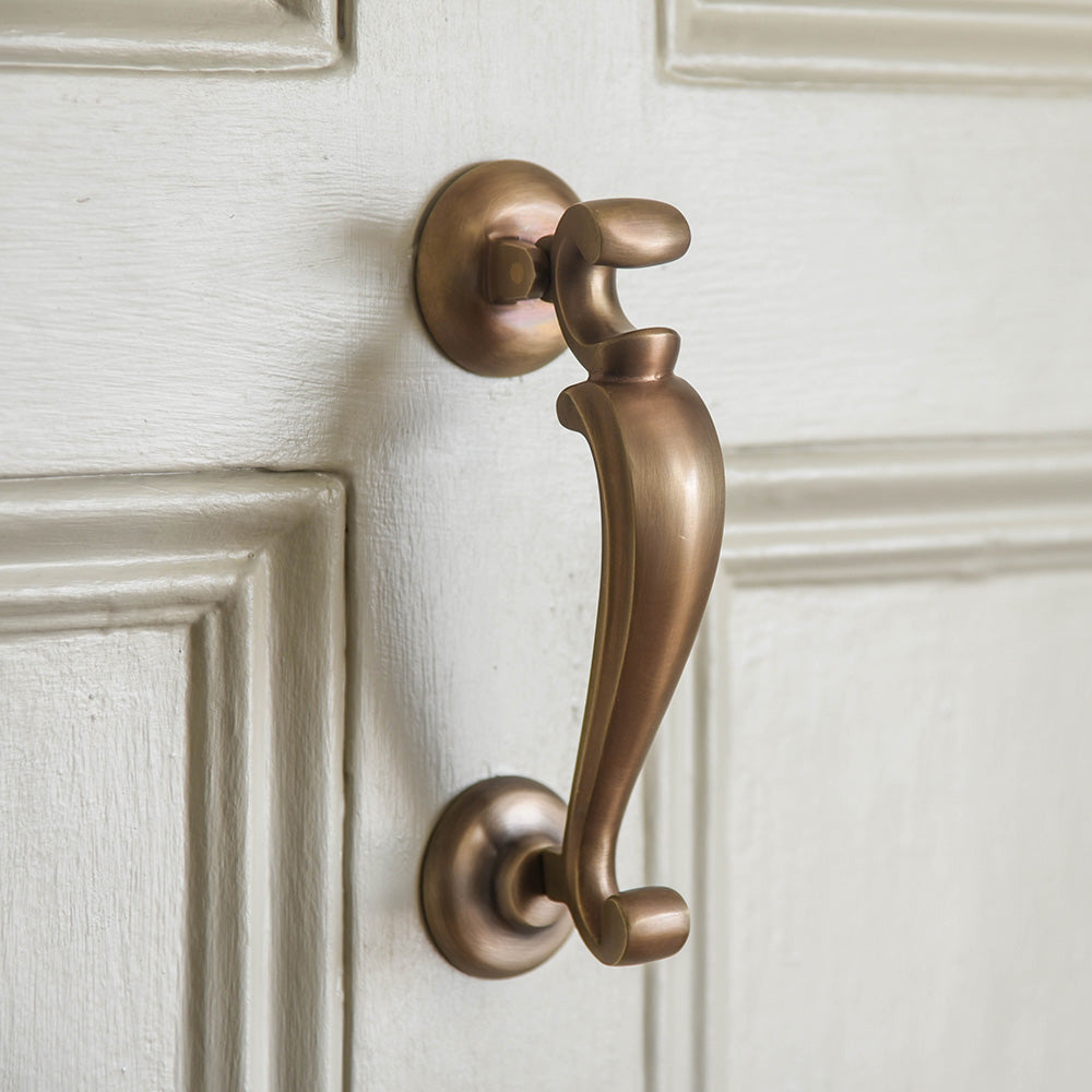 Close up image of solid brass Doctors Door Knocker with unlacquered light antique brass finish on front door.