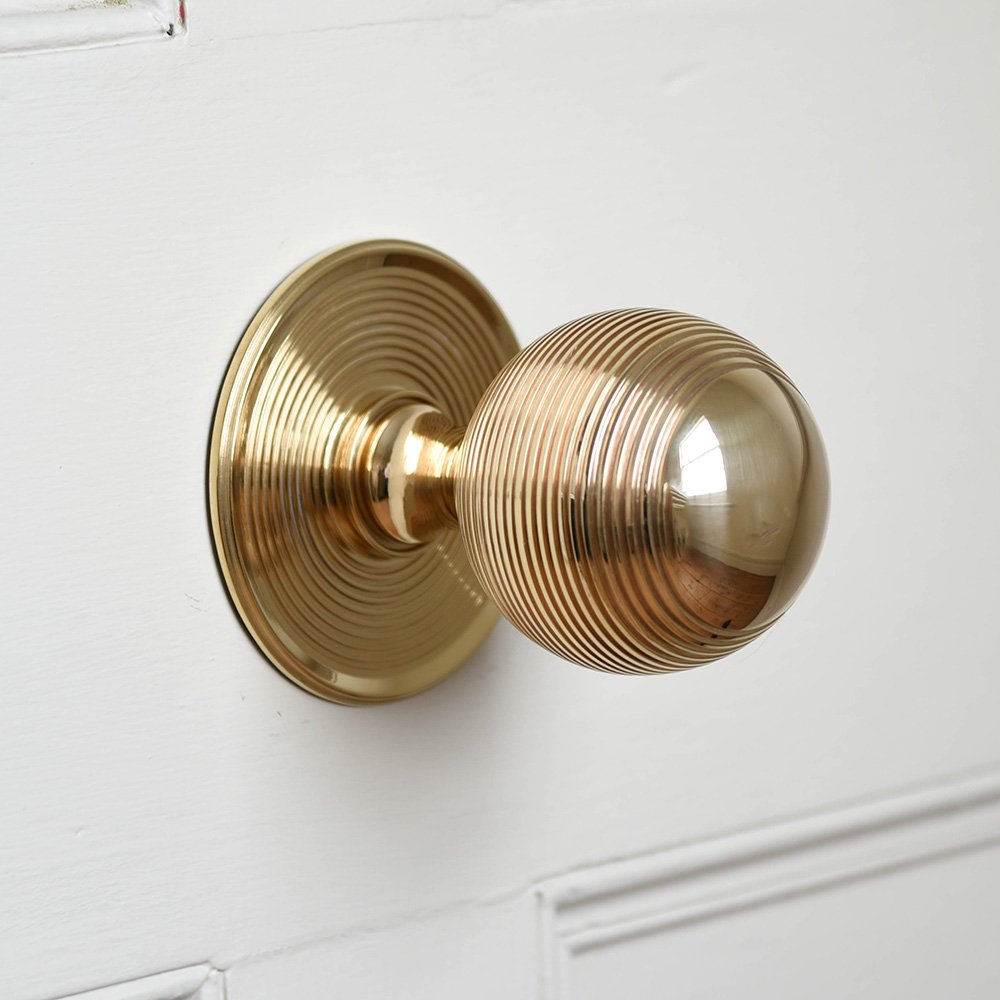 Solid polished brass Large Beehive Door Pull on white door.