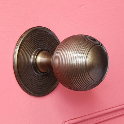 Solid brass Large Beehive Door Pull with distressed antique brass finish on pink door.