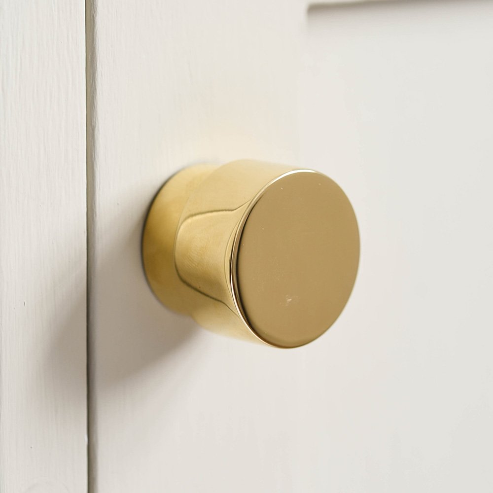 Solid brass drum shaped cabinet knob on cupboard door.