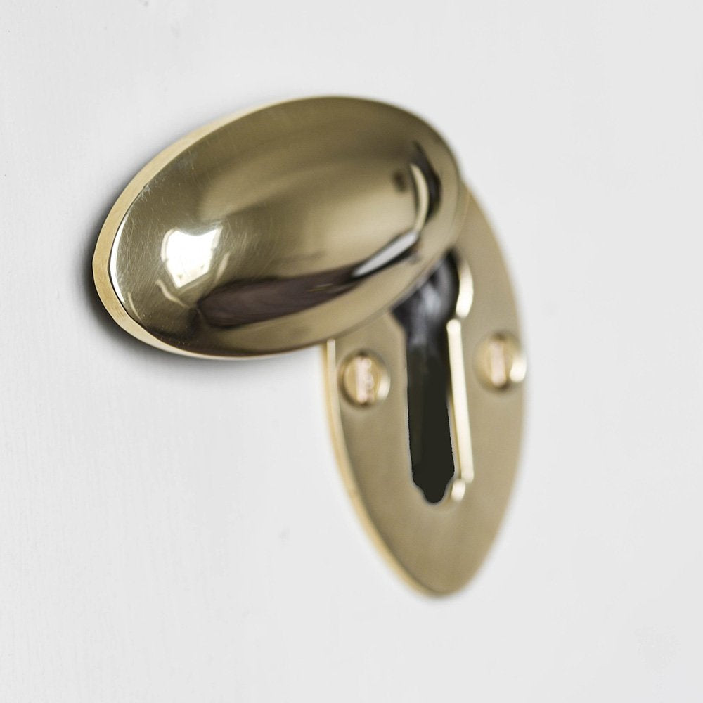 Polished brass oval covered escutcheon with cover open.