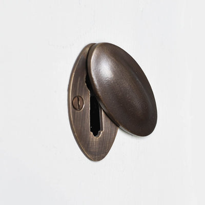 Oval covered escutcheon in distressed antique brass demonstrating inner and outer components