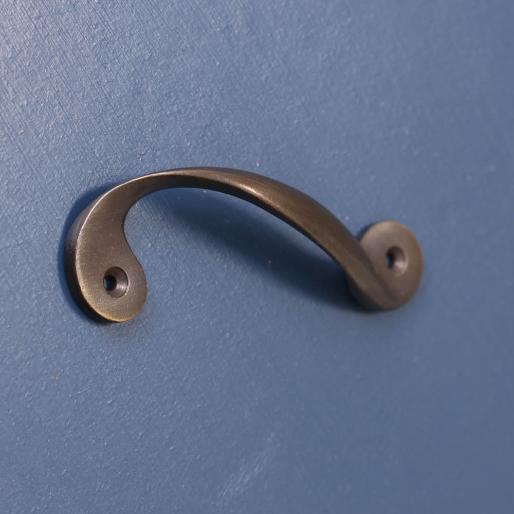 Elegant twisted and curved pull handle in a distressed antique brass finish.