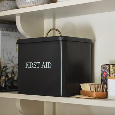 Large dark grey lidded tin with 'first aid' written across the front in white capital letters