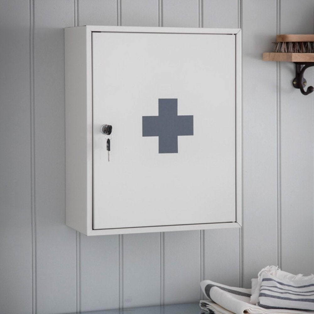 Wall mounted white first aid cabinet with lock and keys. Cross symbol on front of cabinet