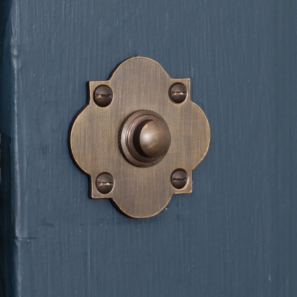 Solid brass Quatrefoil Bell Push in Distressed Antique finish on charcoal door.