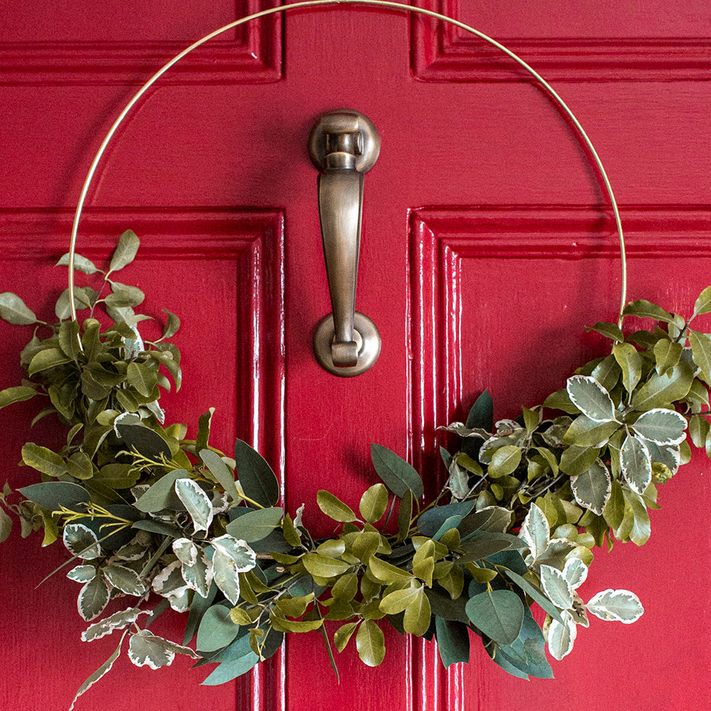 Solid brass Doctors Door Knocker with unlacquered light antique brass finish on front door with wreath.