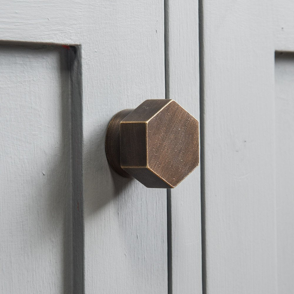 Solid brass Hexagonal Cabinet Knob in distressed antique finish on cupboard door.