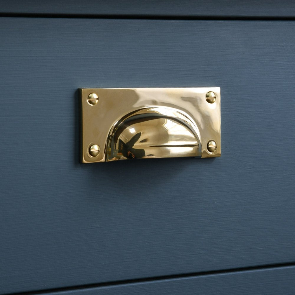 A Hooded Drawer Pull in Polished Brass fitted to a dark blue drawer