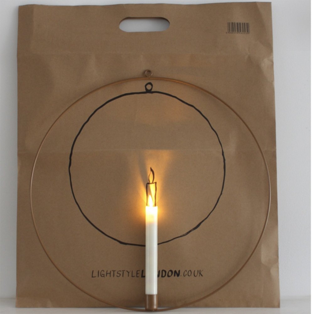 Copper metal ring holding light up dinner style candle with paper packaging