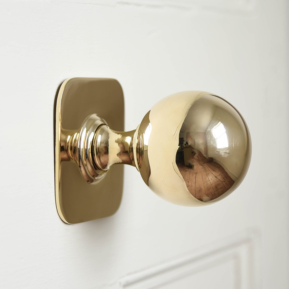 Large Brass Door Pull with Square Backplate on white door.