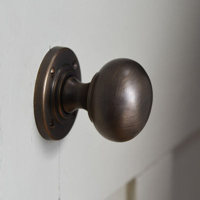 Angled view of Large Bun Door Knobs in distressed antique finish.