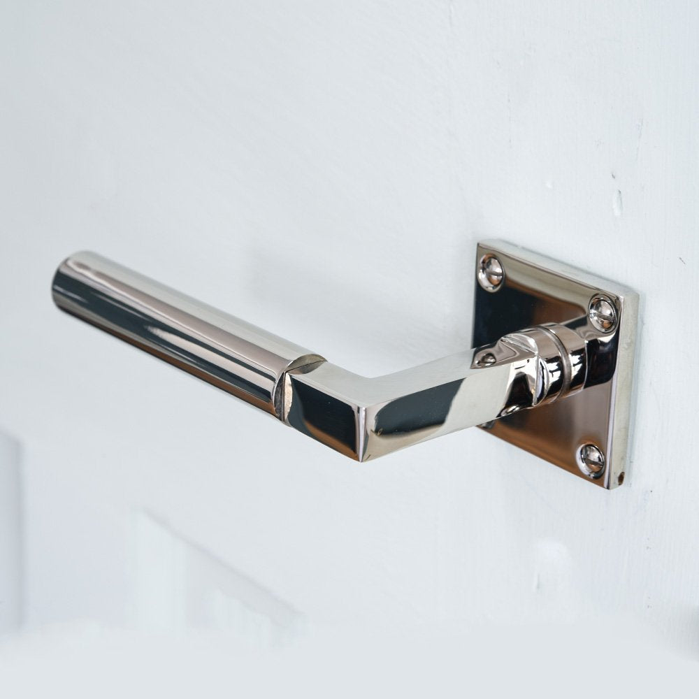 Solid brass Gyllyng Lever Handle on Square Rose with polished nickel finish mounted on door, downward facing view.