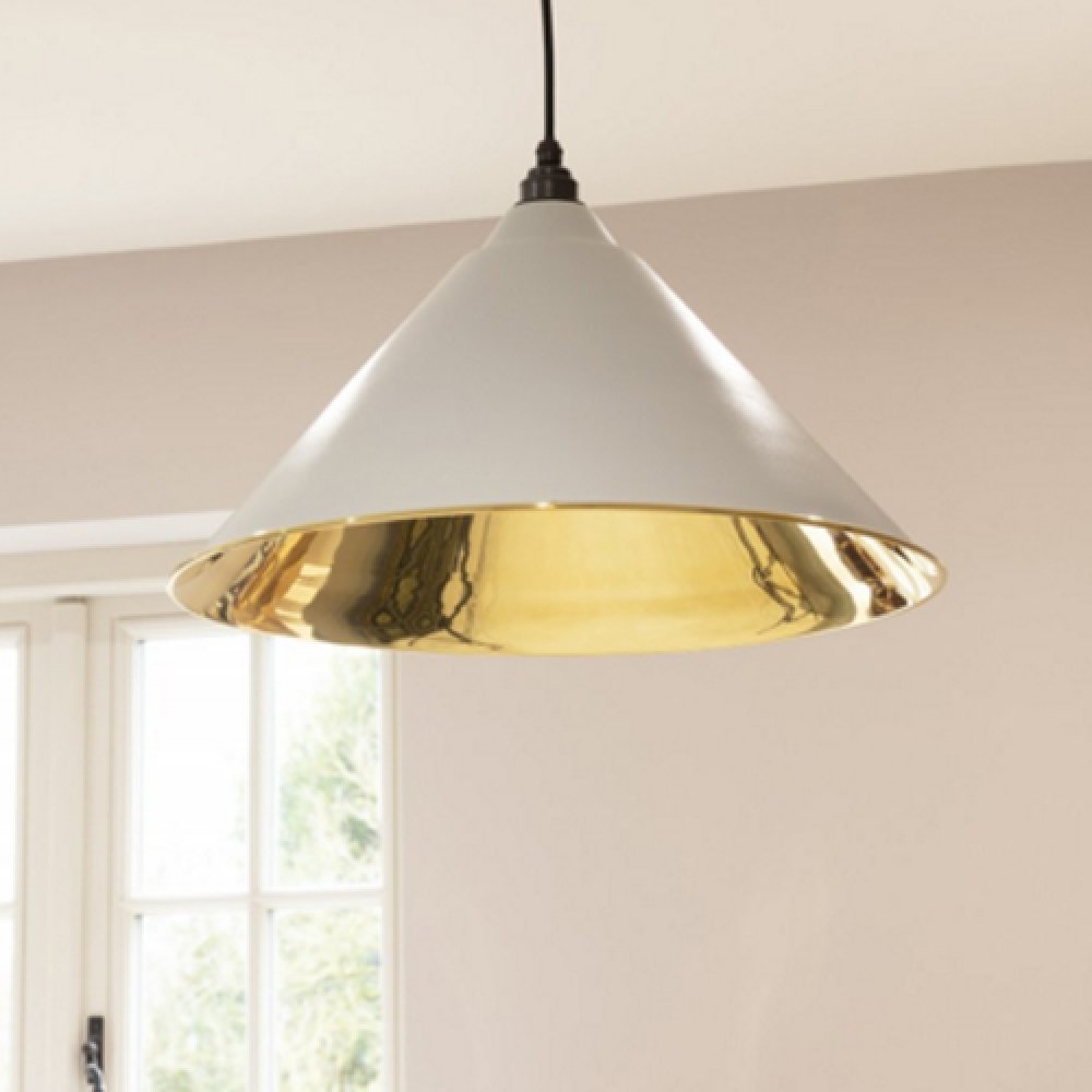 The solid brass pendant light grey exterior and brass interior hanging from a ceiling