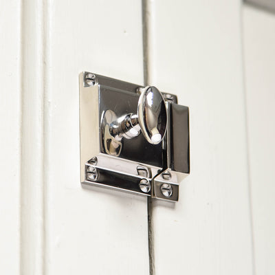 A Sprung oval cabinet latch in polished nickel fitted to a cupboard door