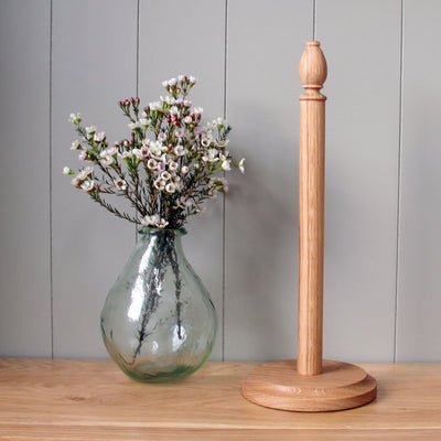 oak kitchen roll holder next to a vase of flowers
