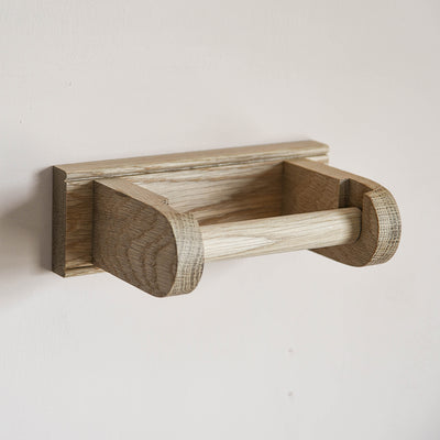 Solid oak loo roll holder fixed to a wall