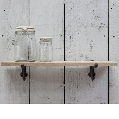 A small raw oak shelf with a pair of cast iron brackets, mounted to wall. 