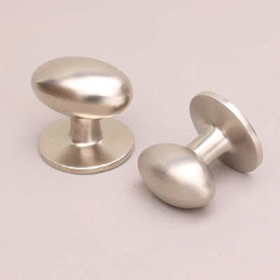Two Oval Satin Nickel Cabinet Knobs on soft pink background.