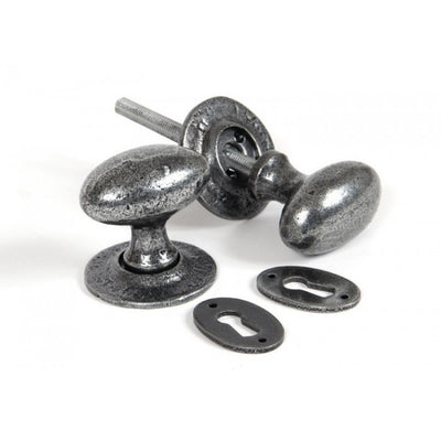 A set of oval door knobs and a pair of keyhole escutcheons in a pewter finish