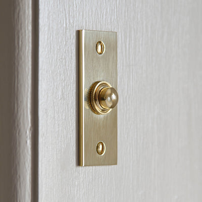 Solid unlacquered Rectangular Brass Bell Push on white door