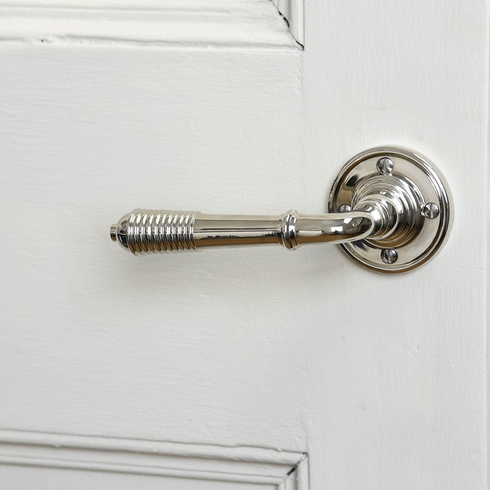 A reeded lever handle on rose set in Polished Nickel