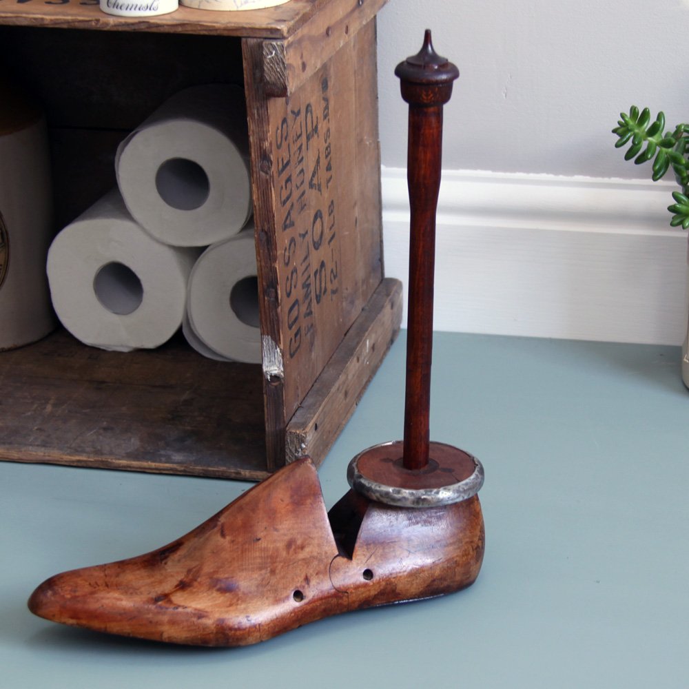 A unique kitchen roll or toilet roll holder created using an antique wooden shoe last and pewter shielded textile bobbin