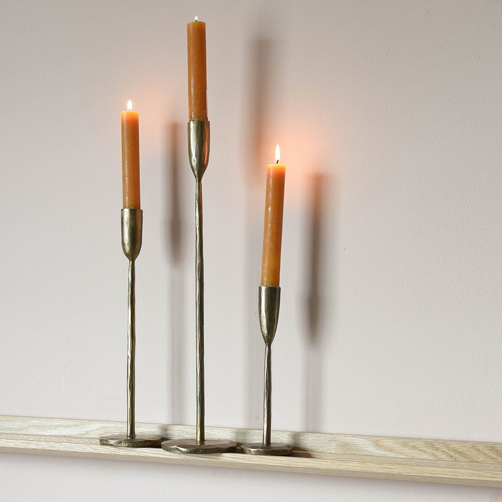 Three Slender Brass Candlesticks in Medium, Large and Small on Wooden Shelf