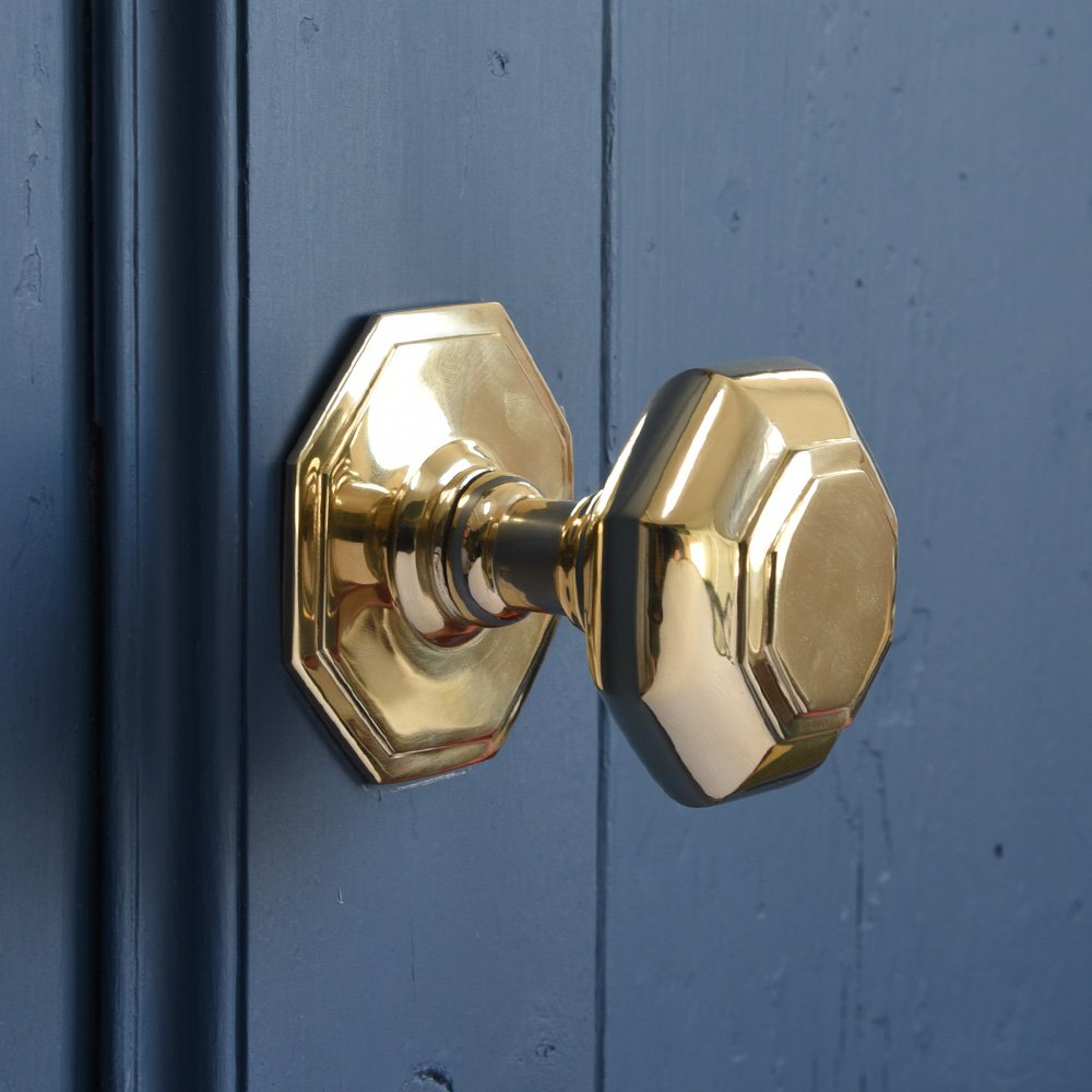 Small octagonal brass door pull on blue background