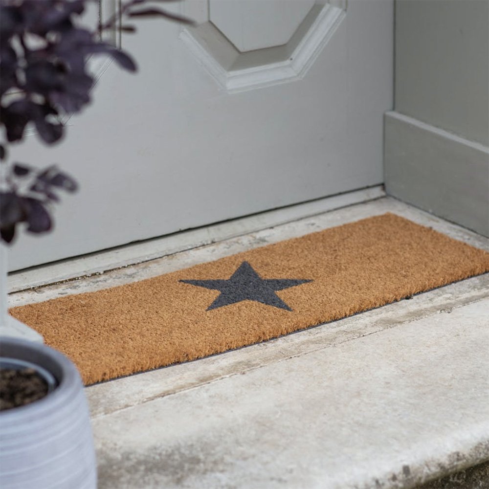 Narrow doormat made with coir. Tan coloured with black star in center.