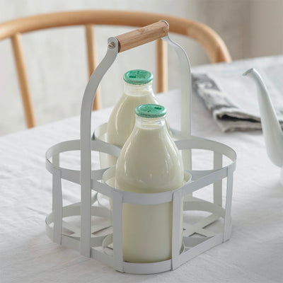 Milk bottle holder crafted in steel in a lily white finish with a wooden beech handle. Holds four standard 1 pint glass milk bottles