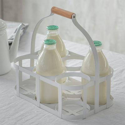 Milk bottle holder crafted in steel in a lily white finish with a wooden beech handle. Holds six standard 1 pint glass milk bottles