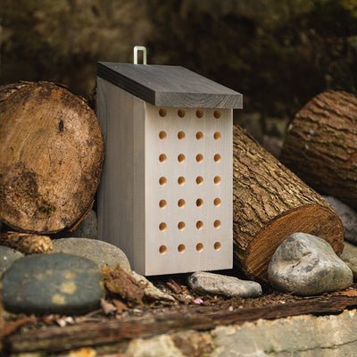Wooden bee house among logs