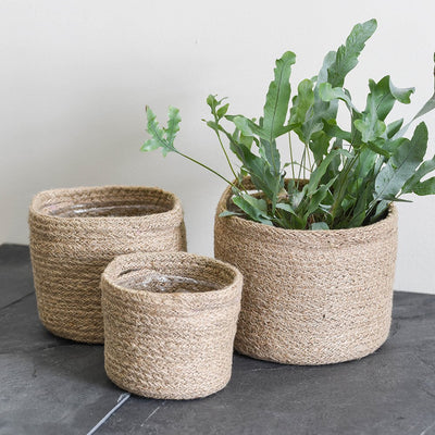 Woven jute plant pots with waterproof lining in set of three sizes that nest into one-another. Medium (left), small (middle) and large (right).